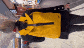 a woman wearing a yellow backpack is walking with a cane