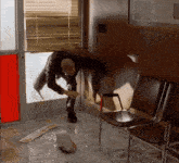 a man is standing in a room with chairs and a broken glass door