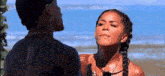 a man and woman are standing next to each other on a beach .