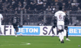 a soccer game is being played in front of a sign that says bet