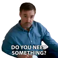 a man in a blue shirt is sitting down and says do you need something