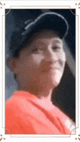 a blurry picture of a man wearing a baseball cap and an orange shirt