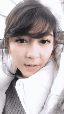 a close up of a woman 's face with a white blanket covering her face