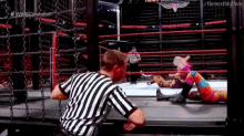 a referee is standing in the middle of a wrestling ring watching a match .