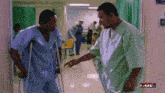 a man with crutches is talking to another man in a hospital hallway with a full logo in the corner