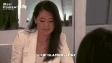 a woman sitting at a table with the words stop blaming that below her