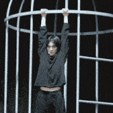 a person hanging from a metal cage with their arms up