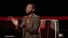 a man in a suit is applauding while sitting in a chair .