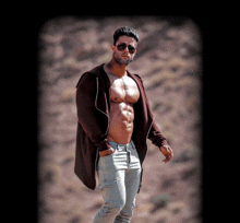 a shirtless man wearing sunglasses and a brown sweater