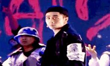 a man wearing a hat and a jacket stands in front of a sign that says ' a '