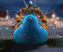 a blue monster is standing in front of a fence with pumpkins