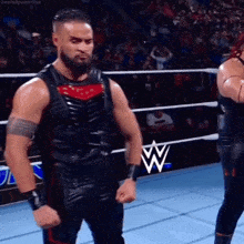 two men are standing in a wrestling ring with their fists up .