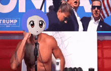 a man without a shirt is sitting in front of a microphone in front of a trump sign