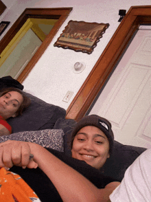 two girls laying on a couch one wearing a north face hat