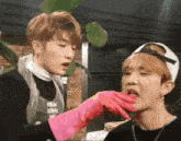 a person wearing pink gloves is feeding another person a piece of food