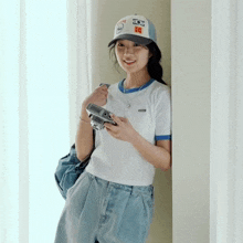 a woman wearing a kodak hat holds a camera in her hand