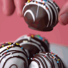 a close up of a person holding a chocolate covered ball with sprinkles on it