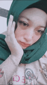 a woman wearing a green head scarf and a bracelet with the letter e on it