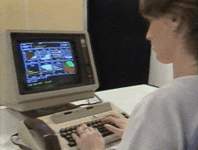 a woman is typing on a keyboard while looking at a computer monitor