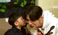 a young boy is kissing a man on the cheek while he is holding tongs .