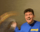 a man in a blue sweatshirt is holding a remote control in his hand .
