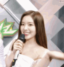 a woman in a white dress is holding a microphone and smiling ..