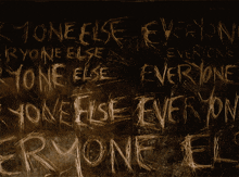 the word everyone is written in white chalk on a dark wall