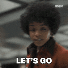 a woman with an afro says let 's go in front of a max logo