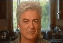 a close up of a man 's face in a kitchen looking at the camera .