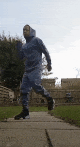 a man in a hooded jacket is running on a sidewalk