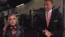 a man in a suit and tie stands next to a woman