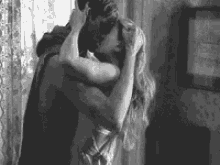 a black and white photo of a man and woman hugging each other .