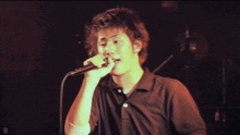 a man singing into a microphone with the letter d visible behind him