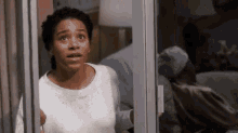 a woman in a white shirt is looking out of a hospital window .
