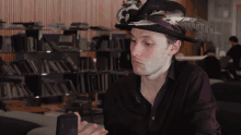 a man wearing a hat with feathers on it holds a microphone