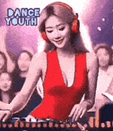 a woman in a red dress is wearing headphones and playing music on a dj mixer .
