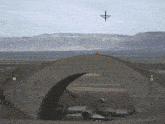a fighter jet is flying over a tunnel with mountains in the background and a sign that says ' a ' on it