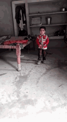 a little boy standing in a room wearing a jacket that says ' avengers ' on it