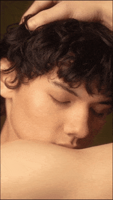 a man with curly hair has his eyes closed