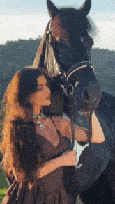 a woman standing next to a black horse holding a glass