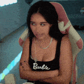 a woman wearing a barbie tank top sits in a chair
