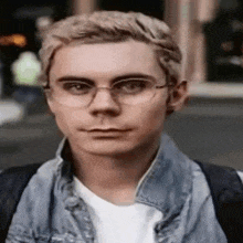 the man is wearing glasses and a denim jacket .