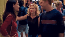 a man and two women are standing in a crowded hallway talking