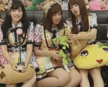 three girls are sitting on a couch holding stuffed animals