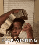 a man is talking on a cell phone while holding a stack of money in his hand .