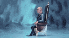 a man in a suit sits in a chair with a crown on it