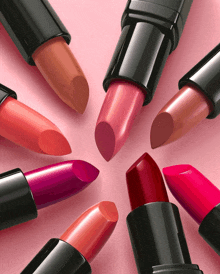 a group of lipsticks are arranged in a circle on a pink surface