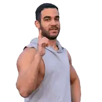 a man in a gray tank top is pointing at the camera