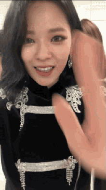 a woman wearing a black top with silver embroidery on the sleeves