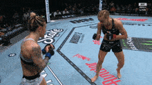 two women are fighting in a ring with a monster energy banner on the floor